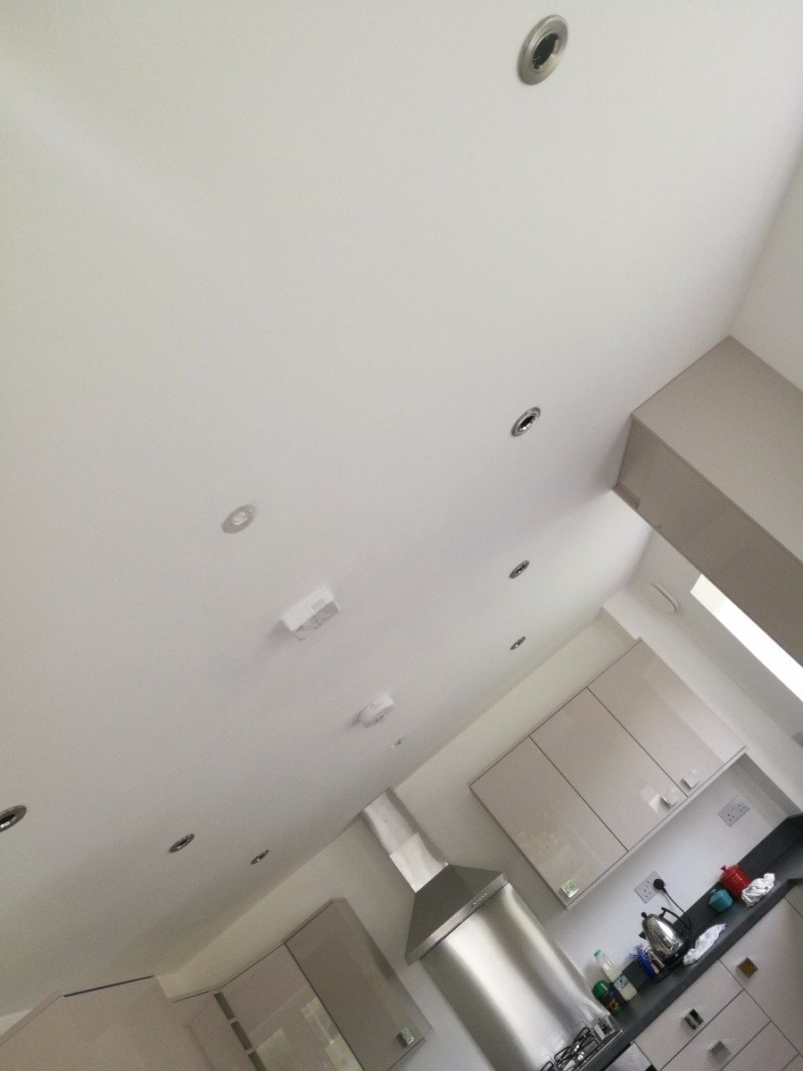A kitchen ceiling fitted with a run of recessed downlights and a ceiling alarm